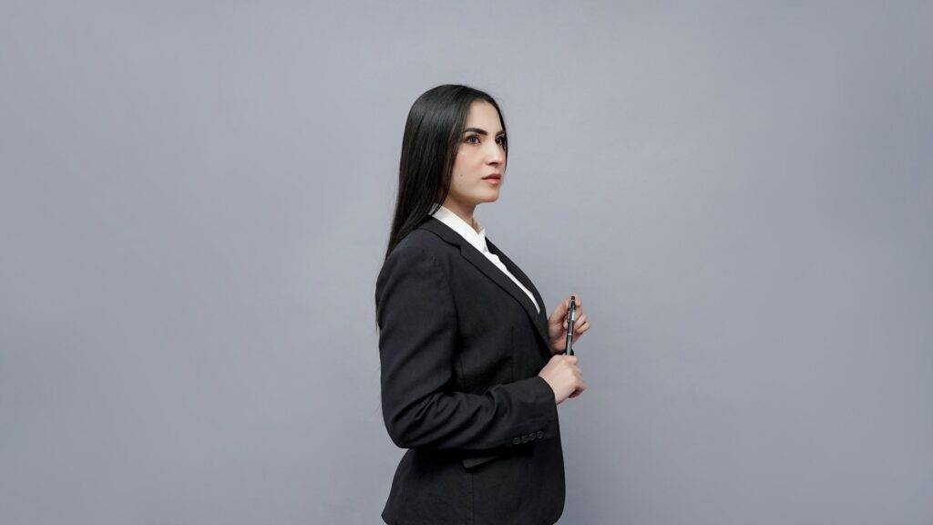 A professional woman in a business suit poses with her hands on, conveying strength and self-assurance.