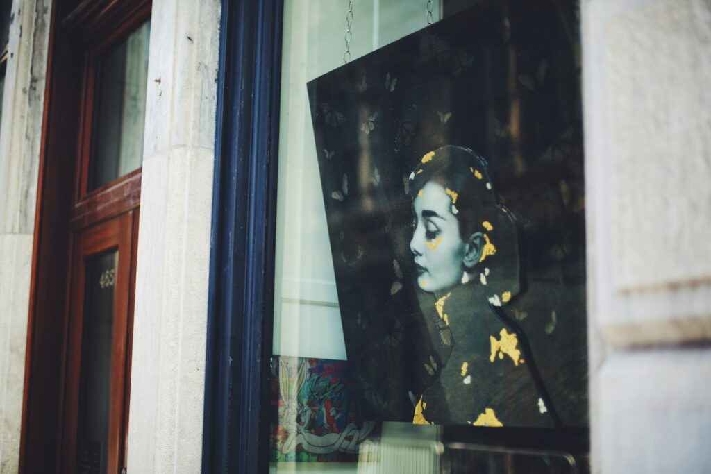 A picture of Audrey Hepburn behind a window, her movie Roman Holiday is one of the best movies to watch in the summer