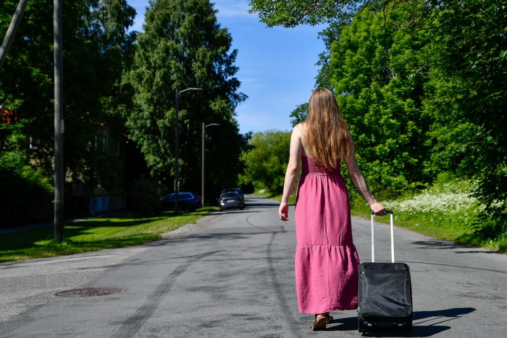 woman in a dress walking down the street with a suitcase