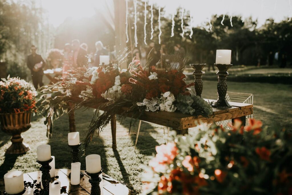 Wedding reception table with mixed floral centerpieces and candle holders in soft sunlight