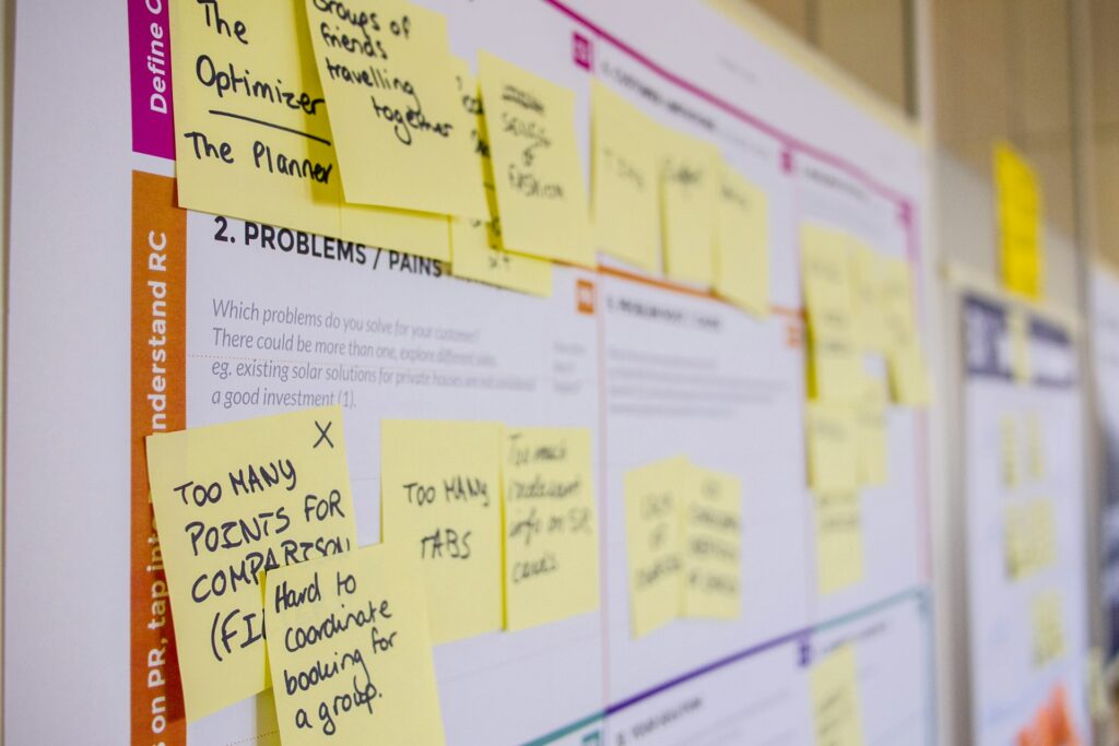 Sticky notes are attached to a brainstorming board labeled "Problems/Pains," featuring handwritten notes. It conveys collaborative planning.