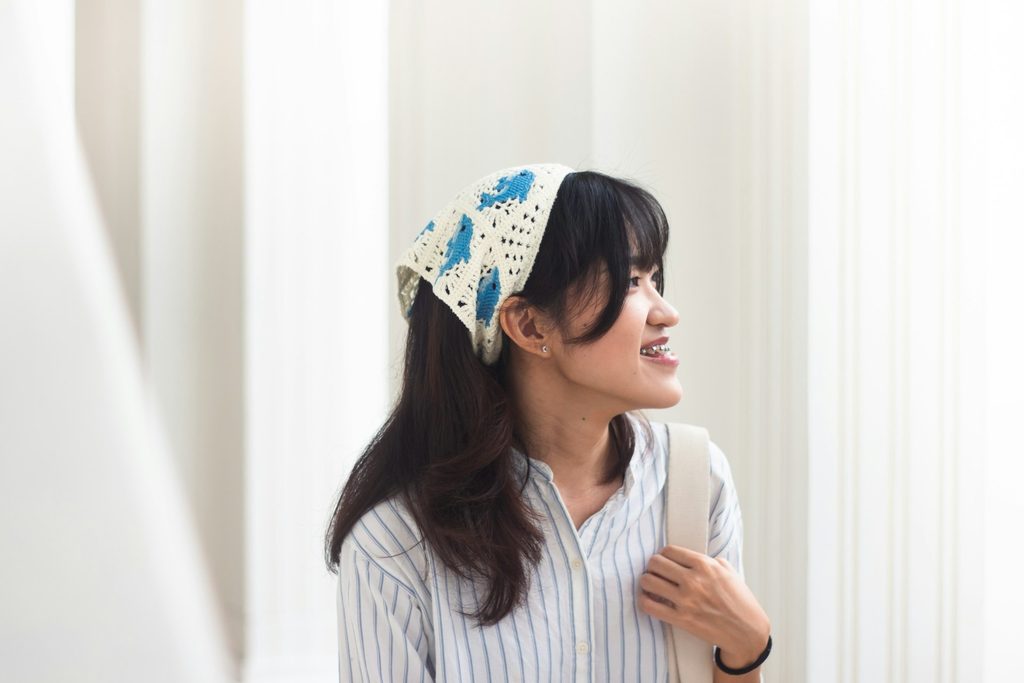 Woman with crochet white bandana with blue dolphins in her hair displaying how to style bandanas