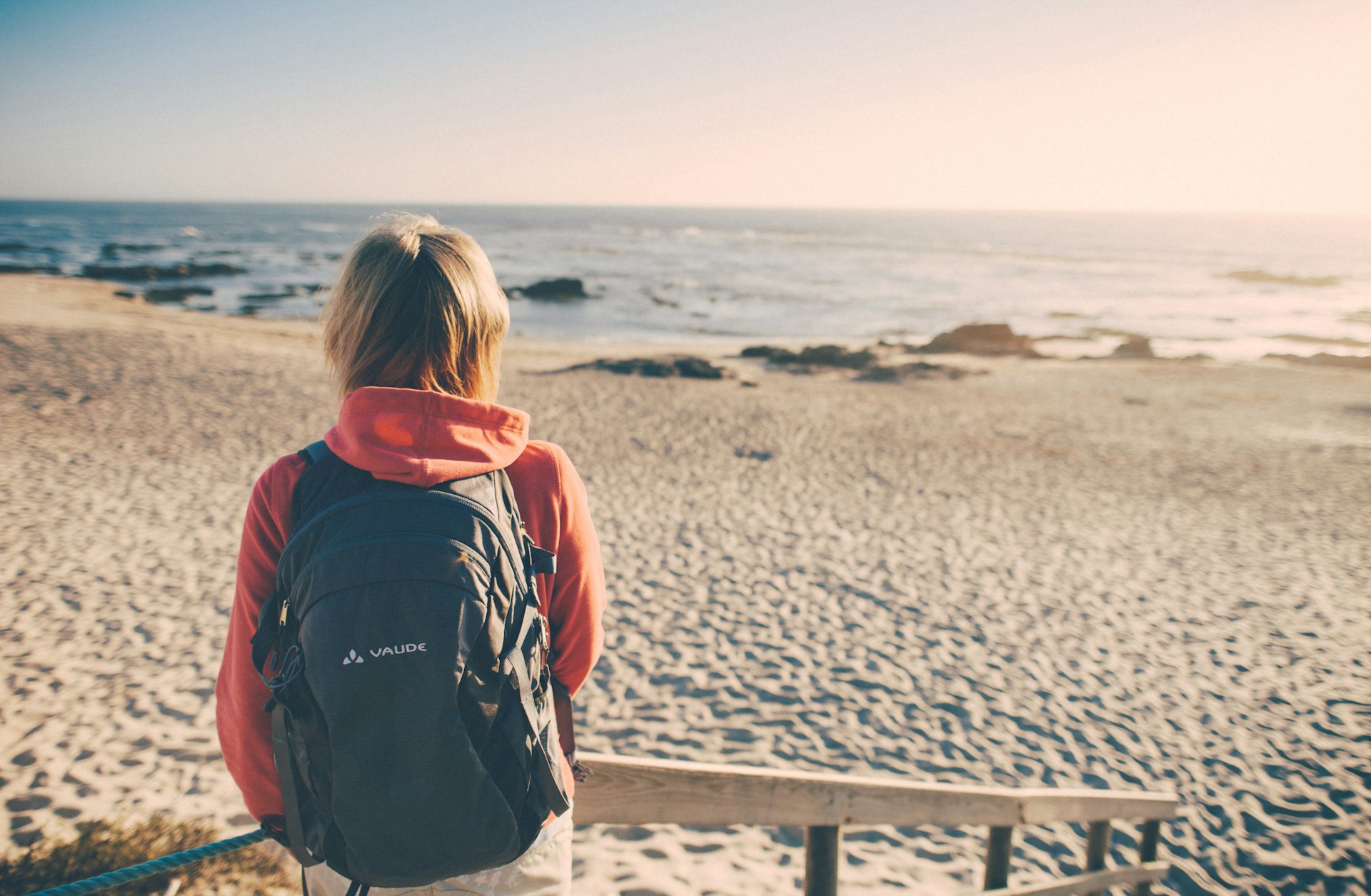 woman in front of a beach with a backpack in the middle of a solo road trip