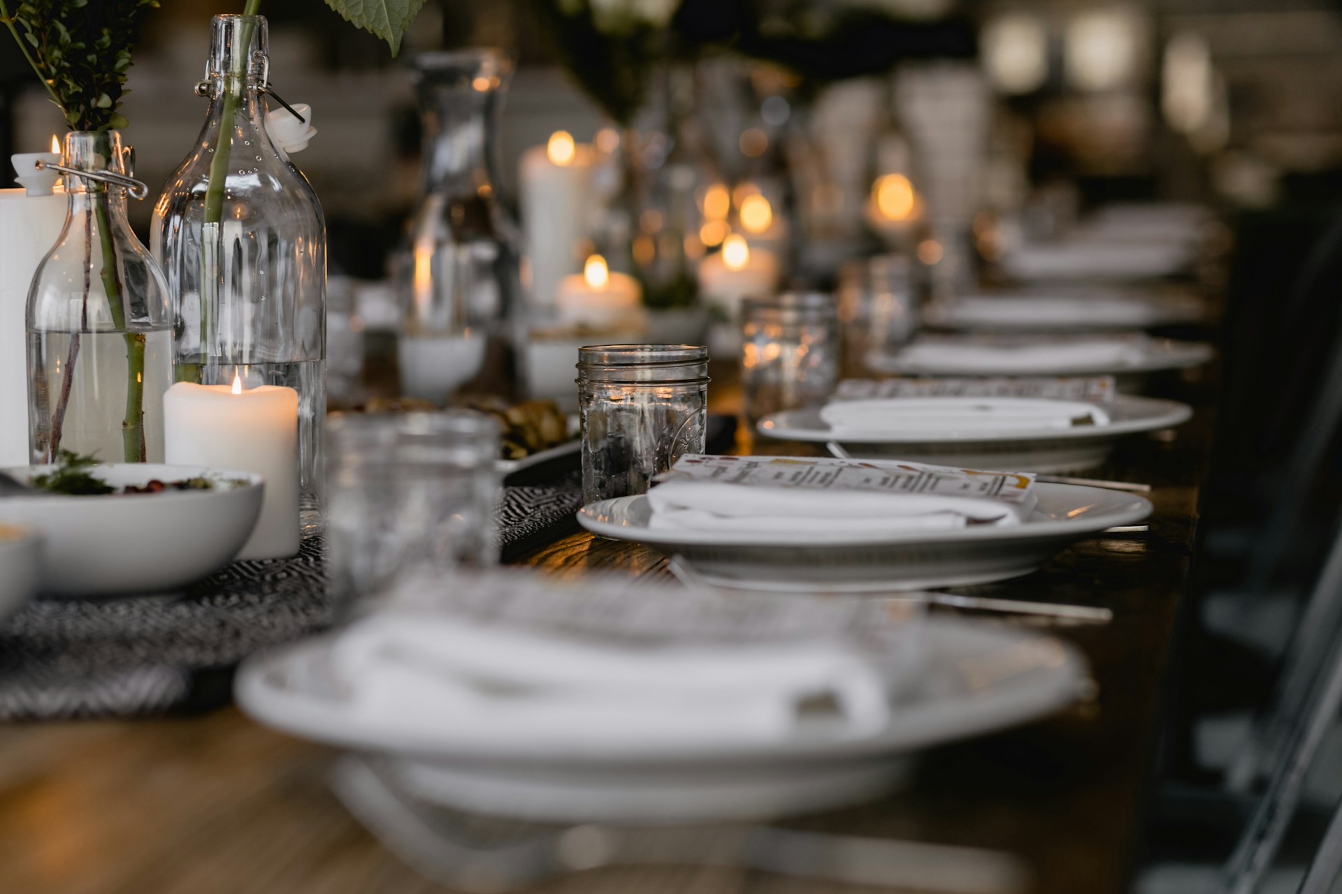 A long dining table set with white plates and elegant place settings, ready for a formal meal or gathering.