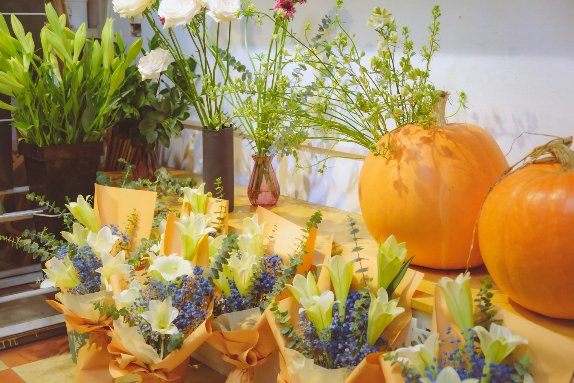 A table adorned with a vibrant arrangement of colorful flowers in various shapes and sizes and pumpkins