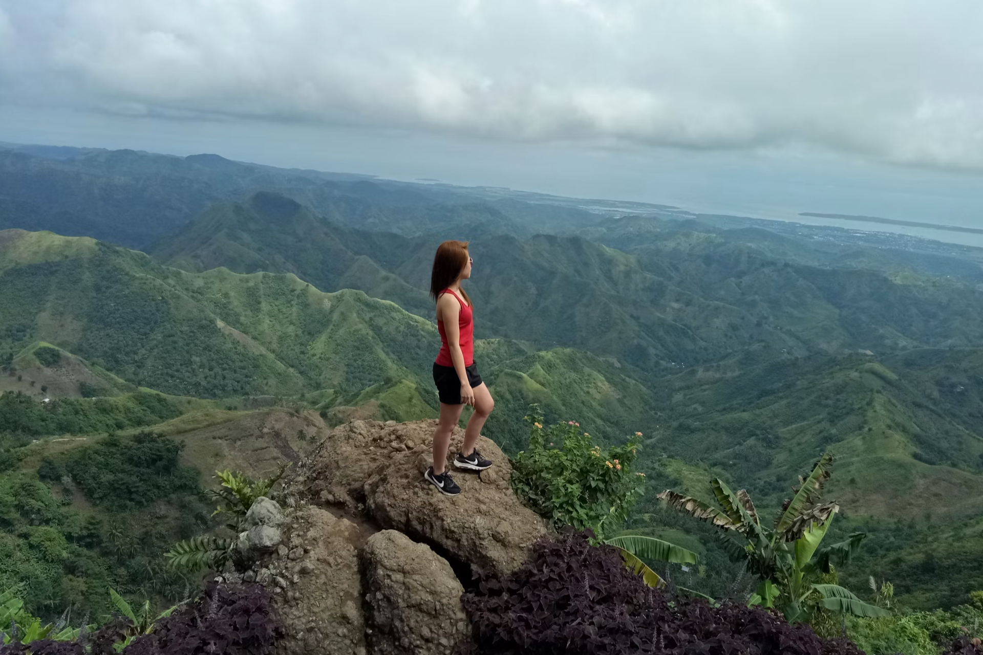 woman in red and black on mountain peak