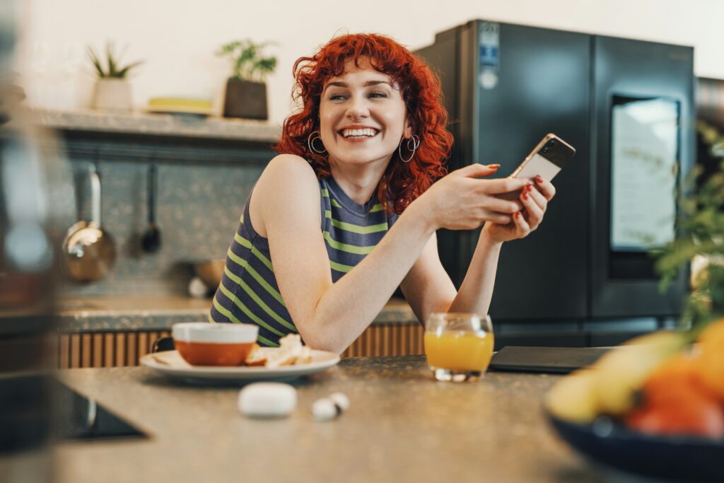 woman sitting and smiling while holding a phone with both hands