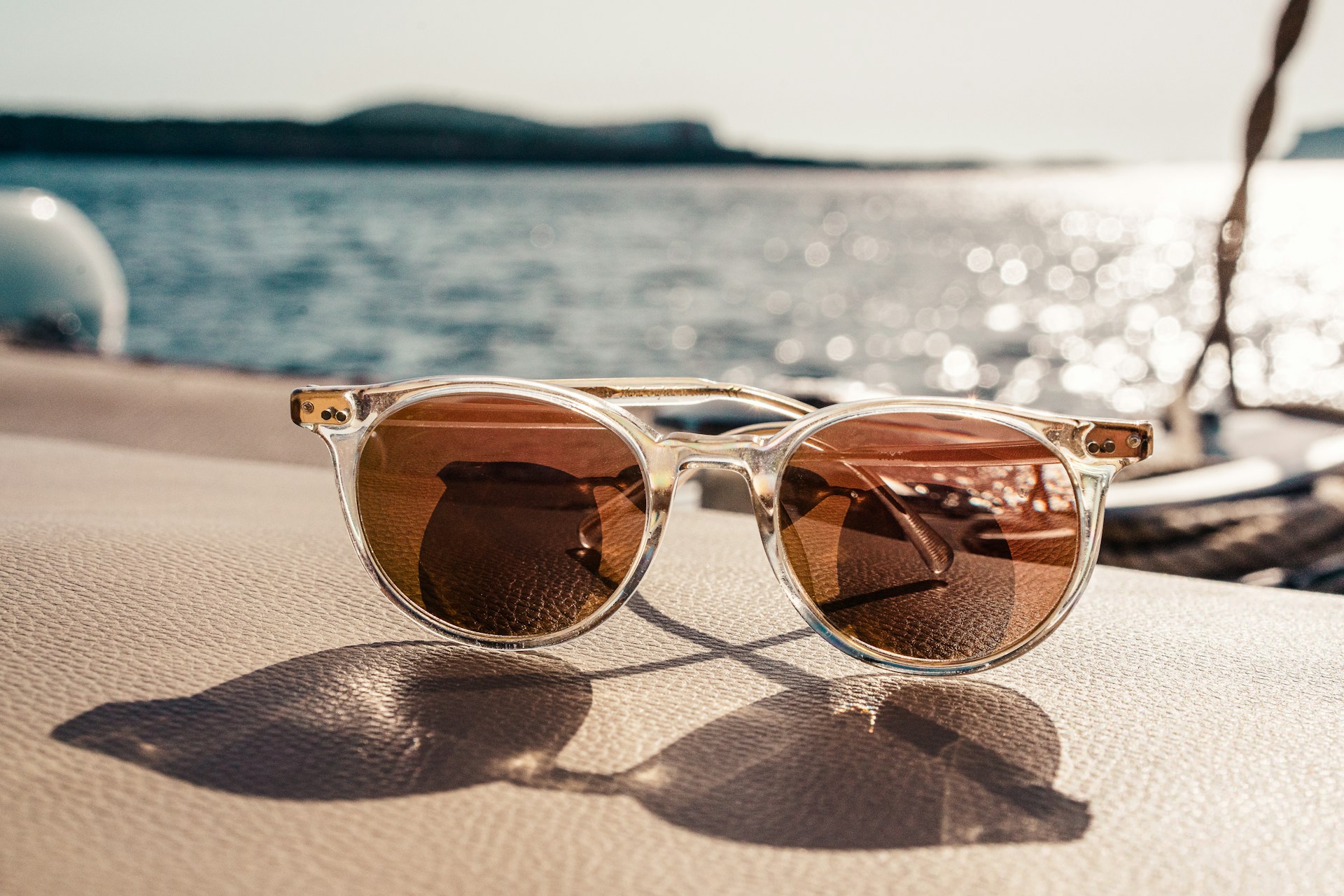A pair of sunglasses placed on a boat, illuminated by sunlight filtering through the lenses, enhancing their colors.