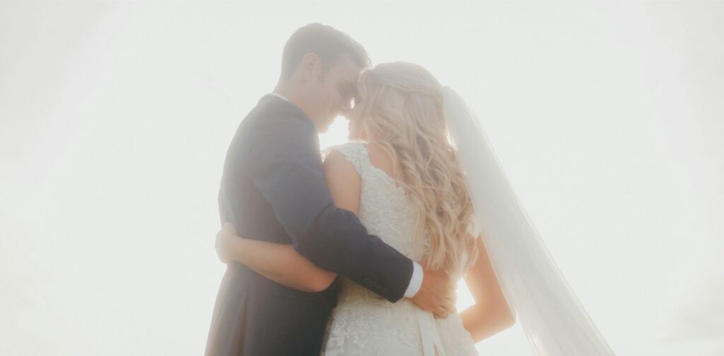 A bride and groom with their arms around each other.