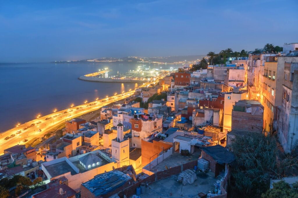 Aerial view of a coastal city skyline glowing at sunset above the water