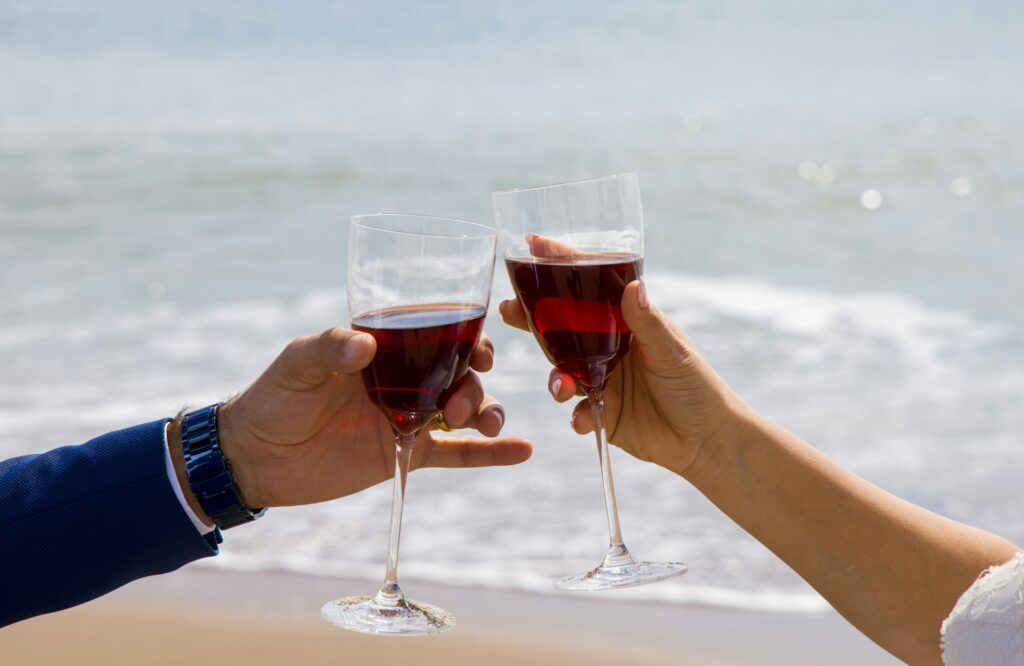 Bride and groom doing a cheers with wine glasses on a beach