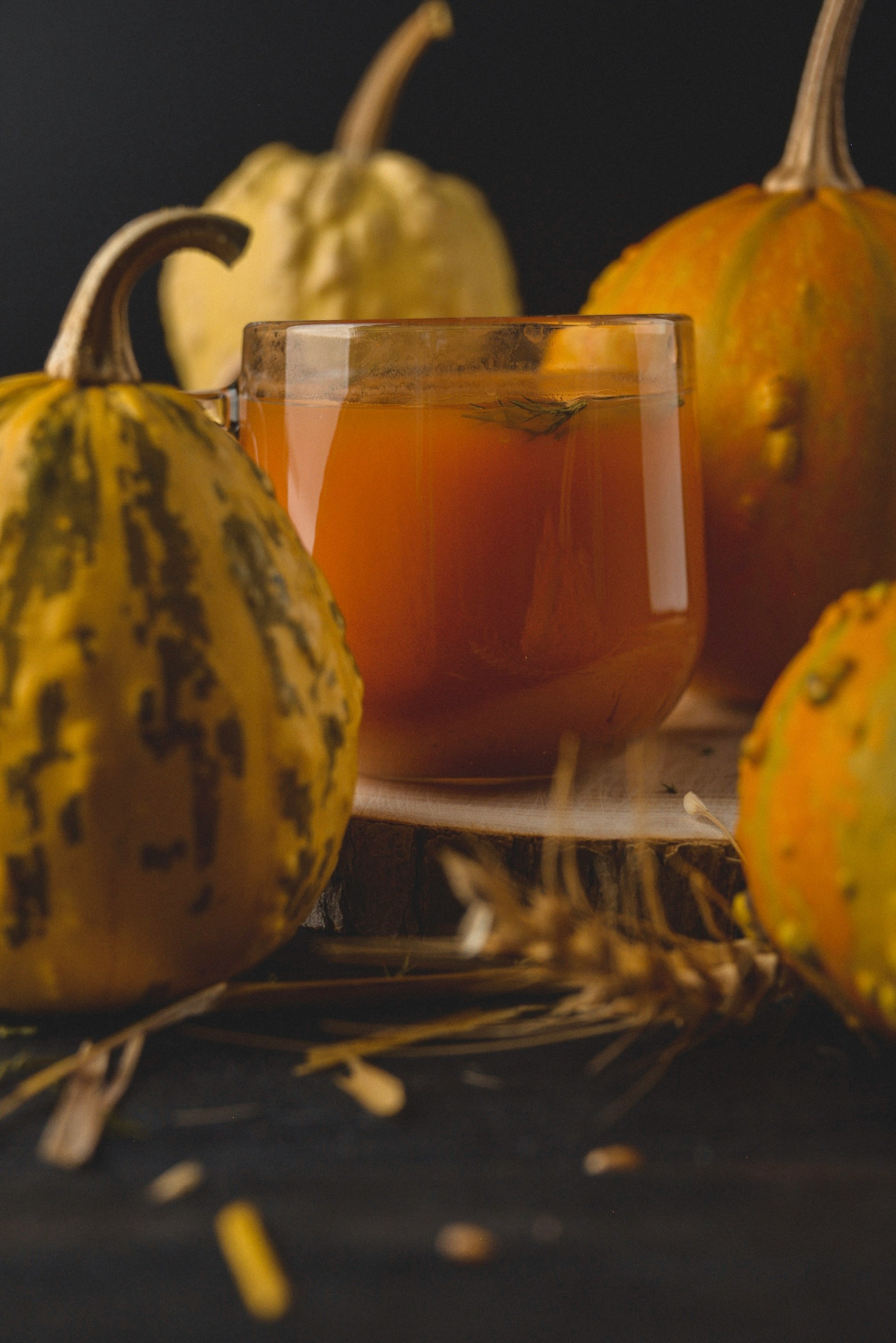 Orange cocktail surrounded by gourds and pumpkins