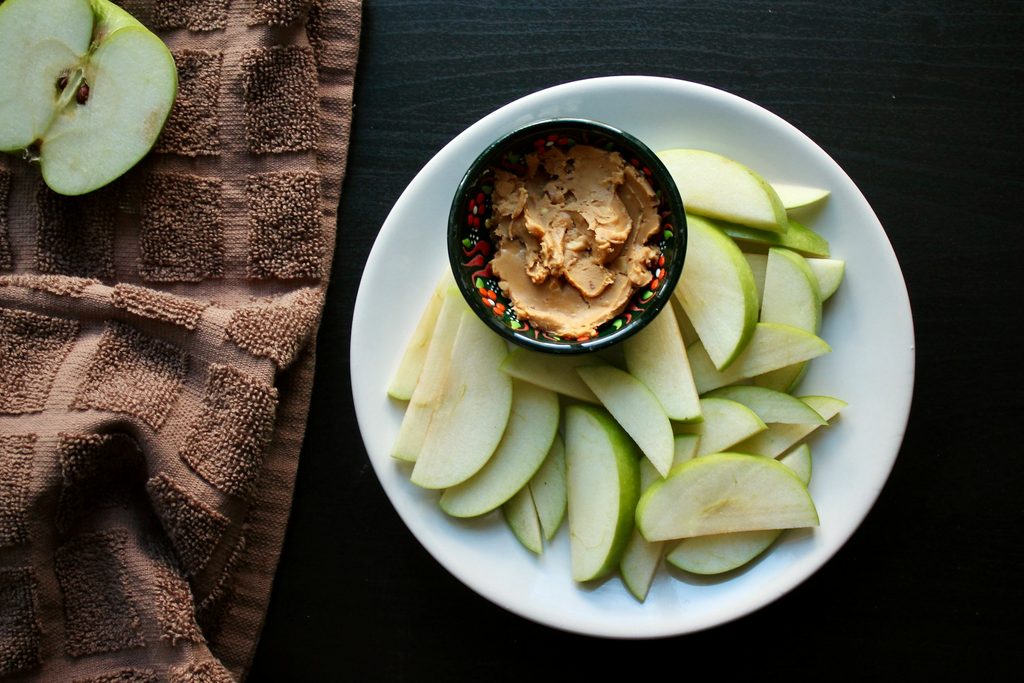 Sliced apples and a bowl of peanut butter