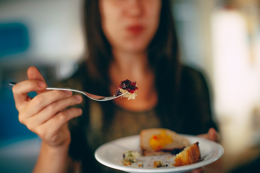 Woman holding fork with fruit tartte up