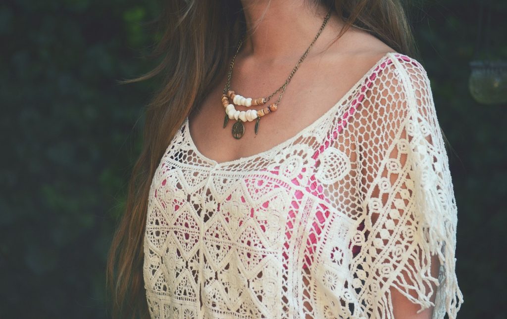 Closeup o boho crochet white top, beaded necklace