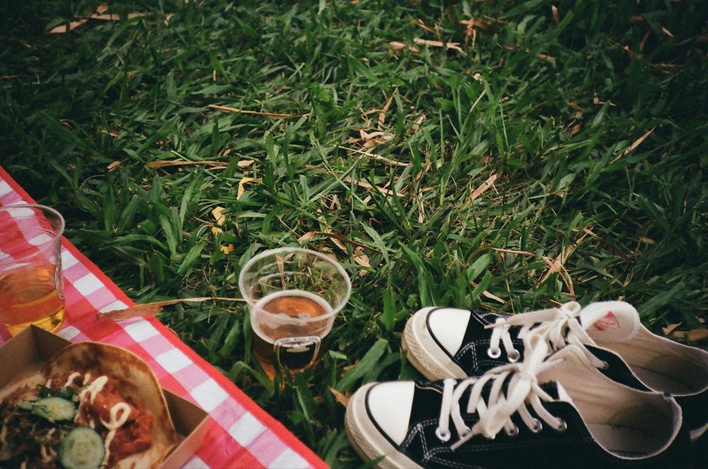 Converse, beverage, picnic blanket and food on grass
