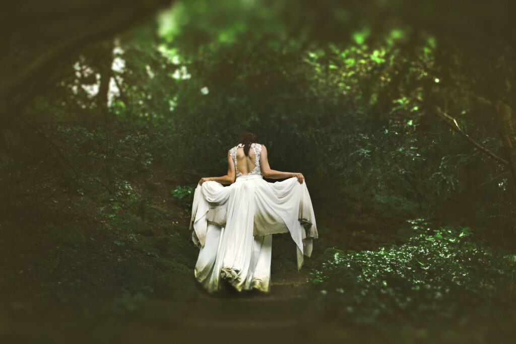 A bride walking through a dark forest. 