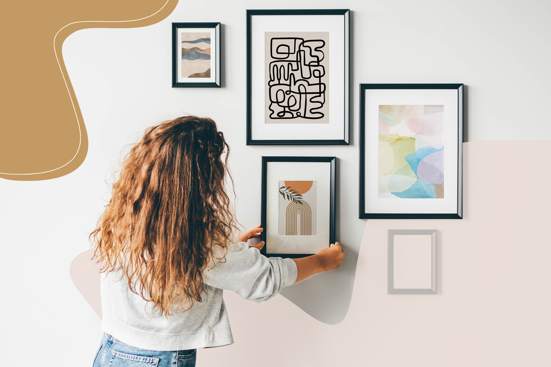 A woman with curly hair adds a picture with a black frame to her gallery wall, one of the easiest ways to decorate your walls.