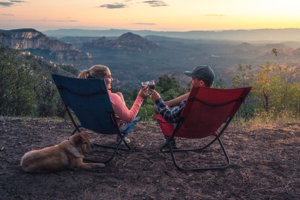 A man and woman sit in lawn chairs with a dog overlooking a canyon.