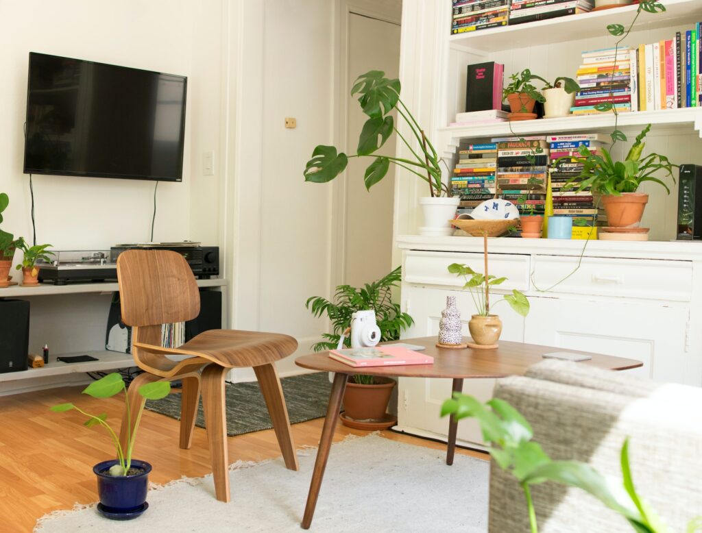 An apartment is decorated with plants, books and simple furniture.