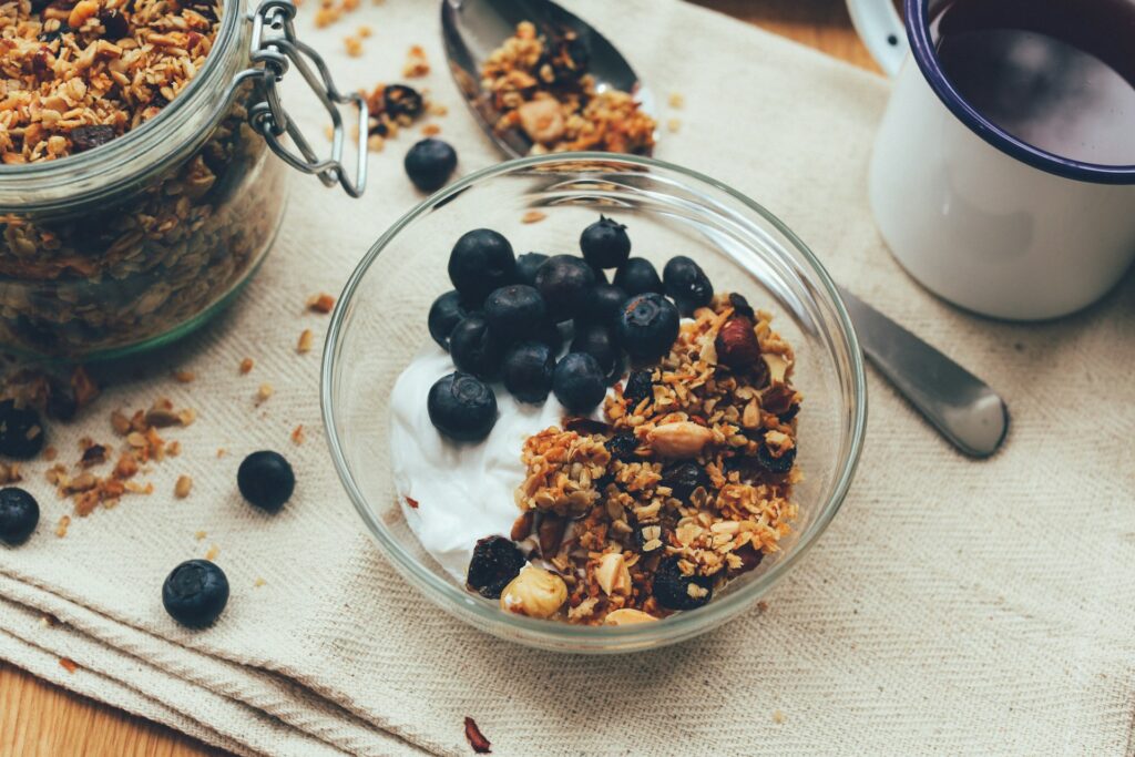 A bowl of yogurt, granola and blueberries.