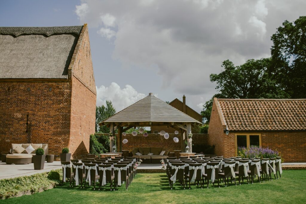 An outdoor wedding venue features rows of chairs facing a gazebo. 