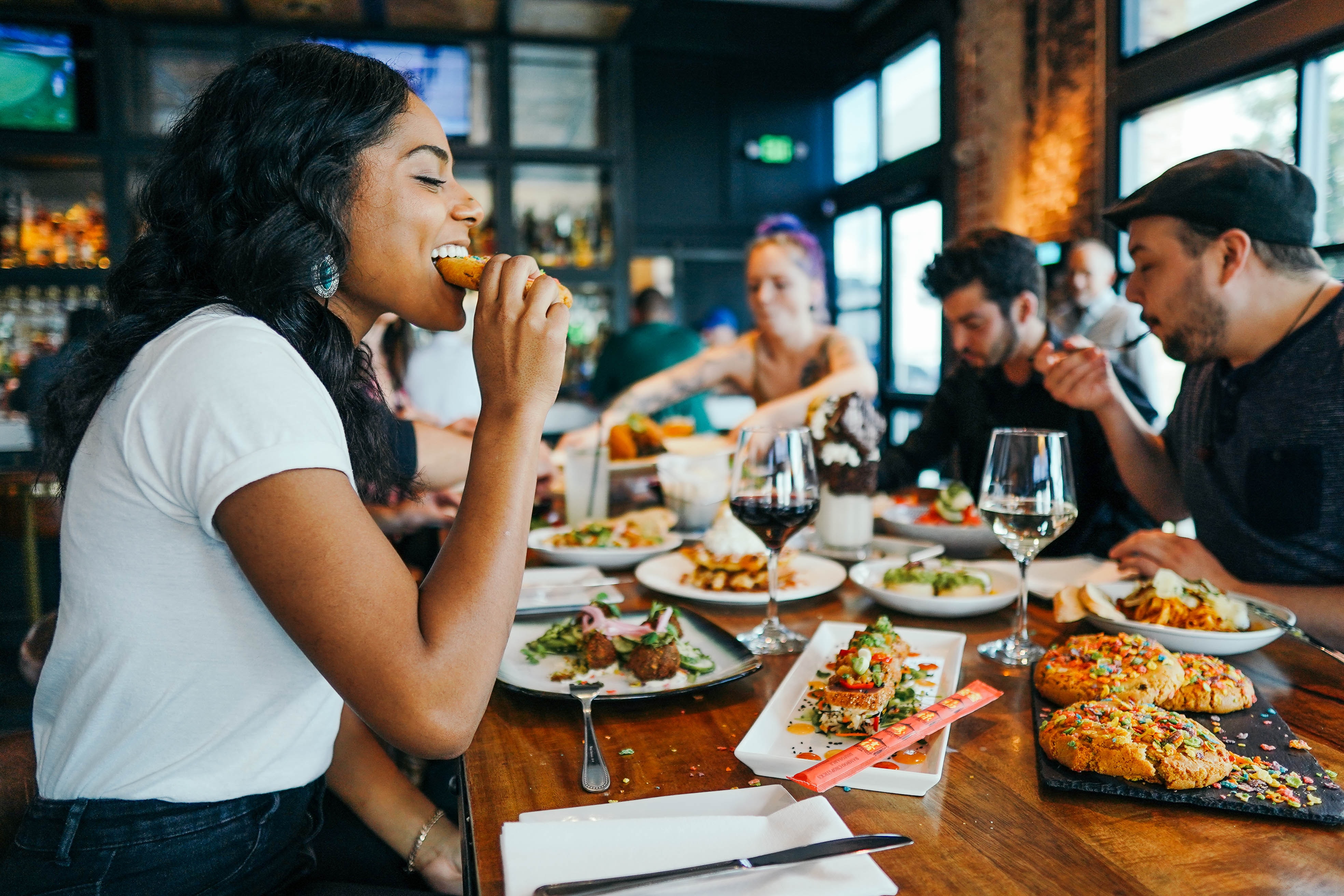 A woman takes a bite of food at a restaurant.