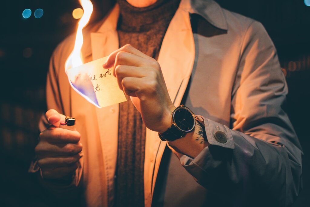 A person holds a burning slip of paper.