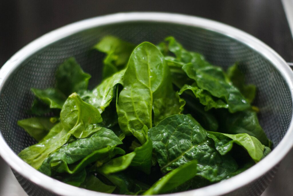 Green spinach sits in a strainer.