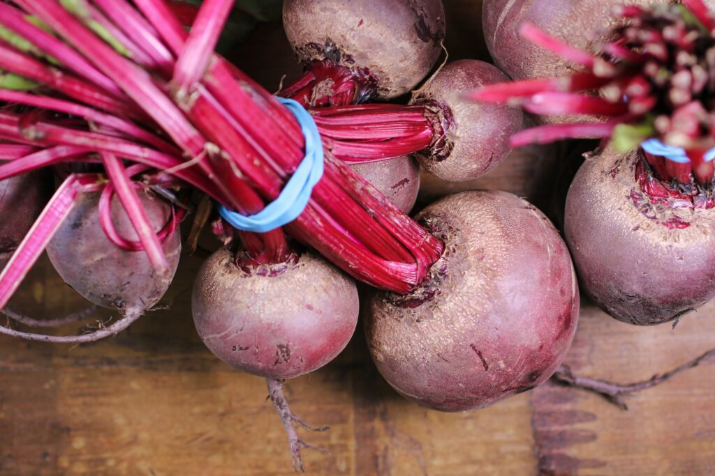 A bundle of red beets sites on a table.