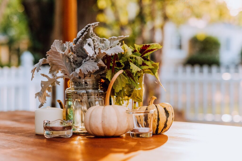 A centerpiece with pumpkins and leaves in vases.