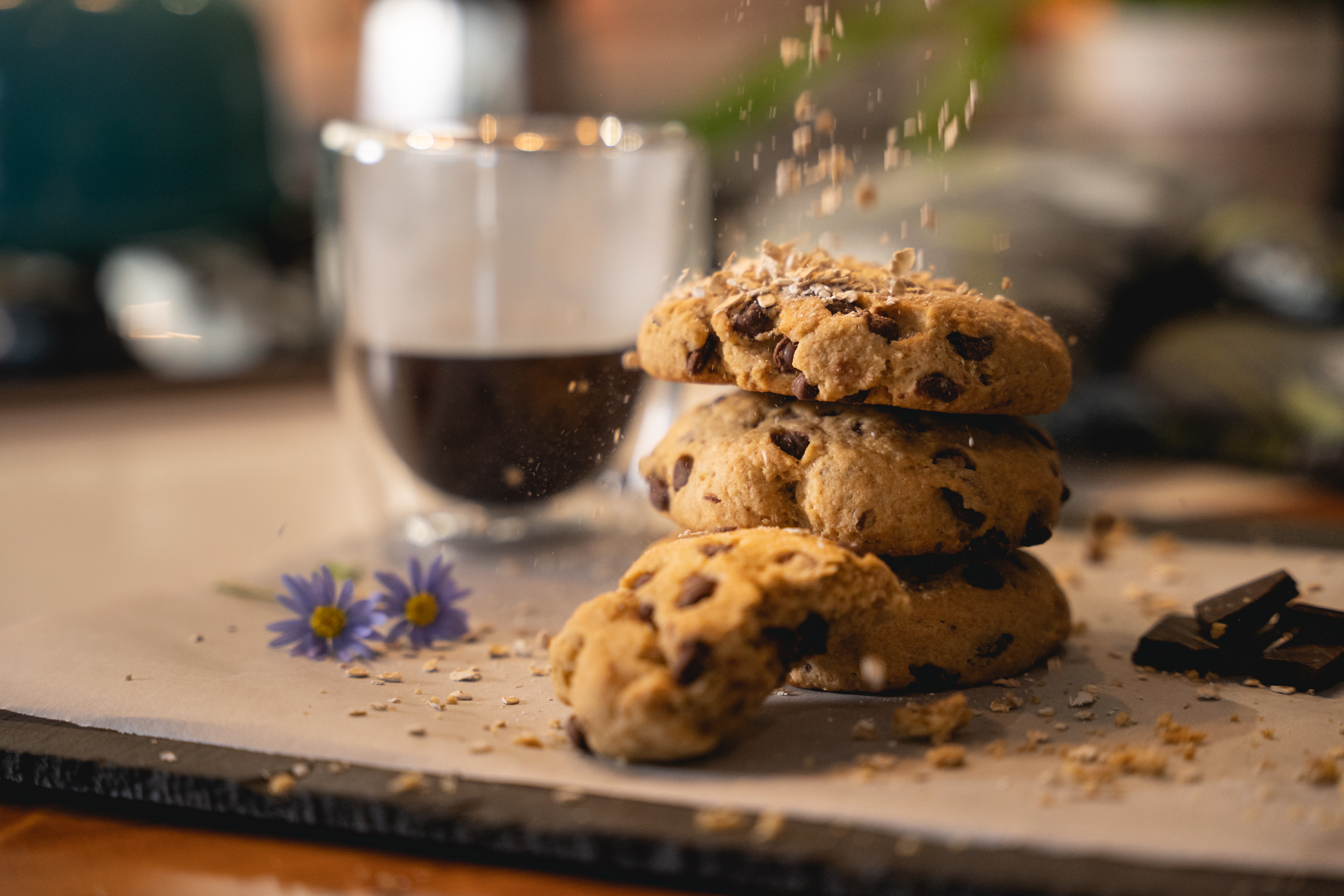 Chocolate chip cookies sit on a table next to a cup of coffee.