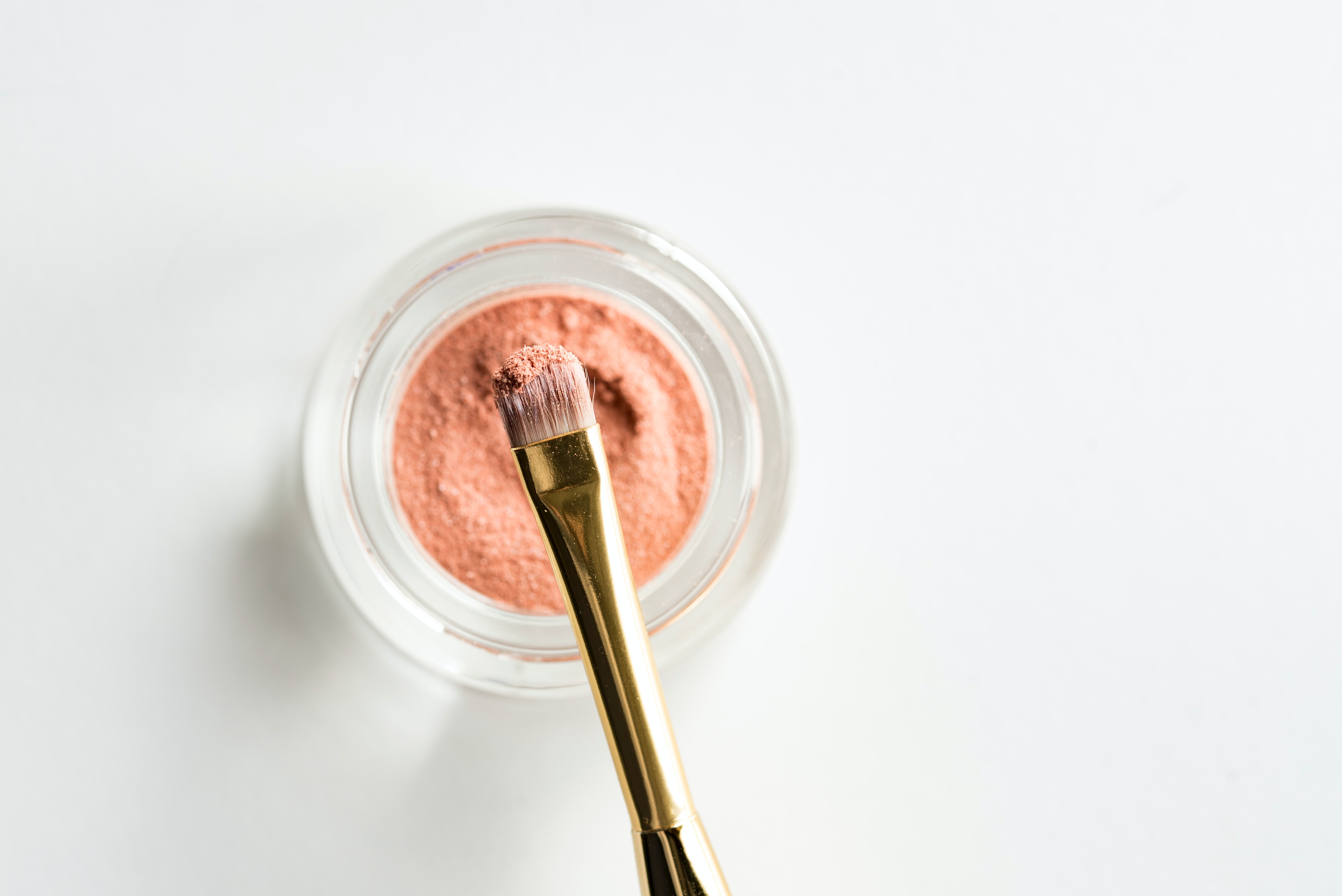 A makeup brush dipped in pink powder. 