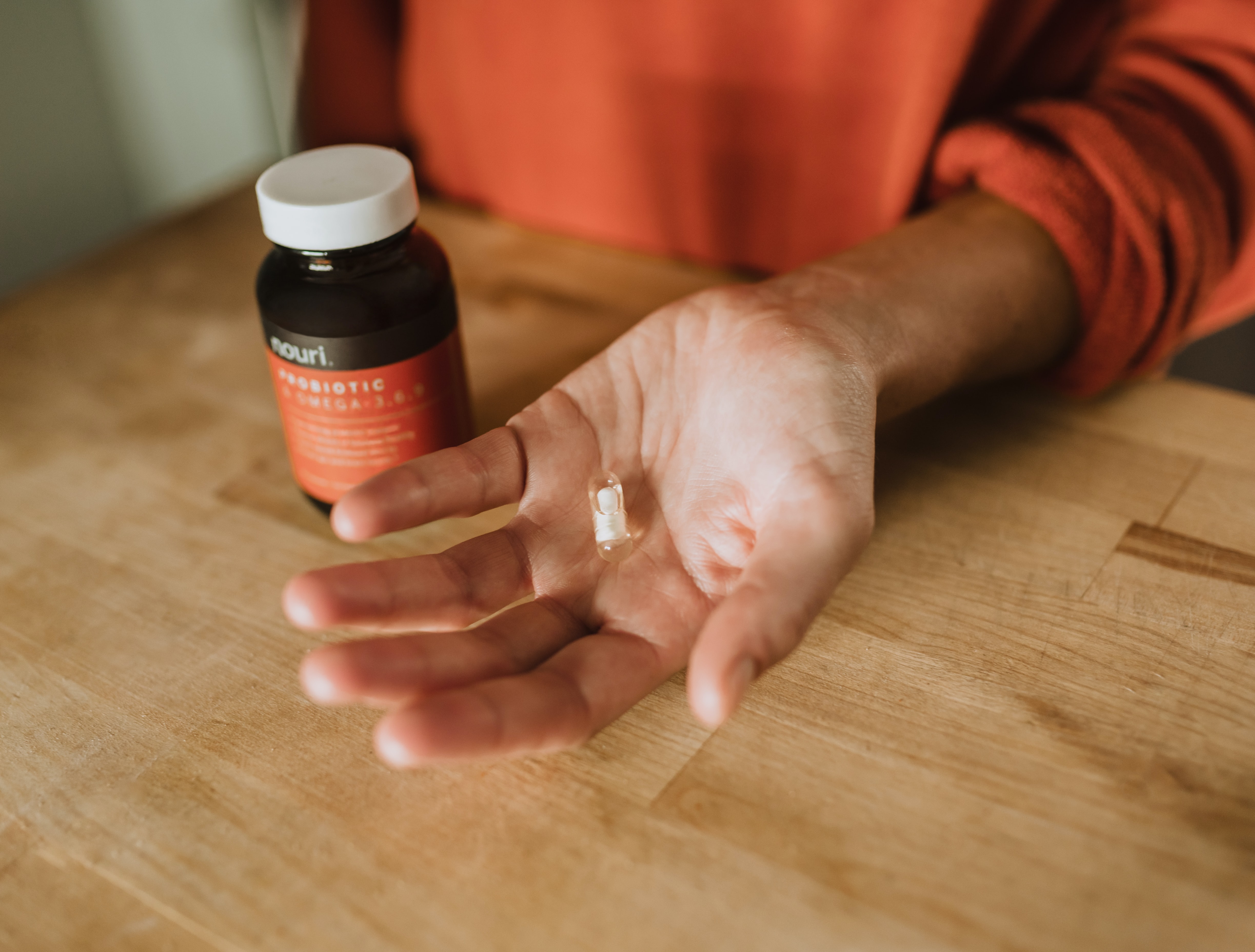 A person holds a multivitamin pill in their hand.