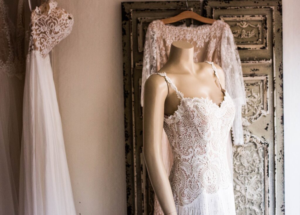 Wedding dresses are displayed on hangers and a mannequin. 