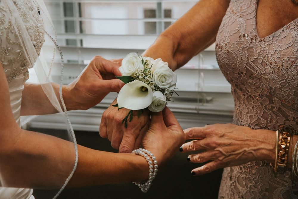 bride giving mother a flower corsage