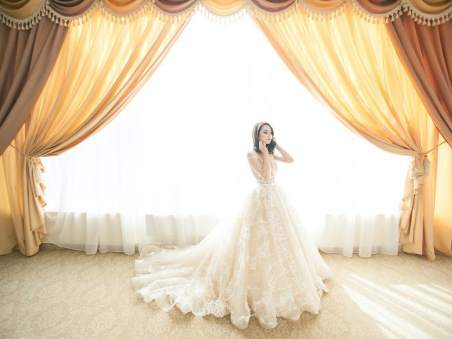 One of the beautiful gold embroidery wedding dresses against a backlit curtain with rich, warm color tones.