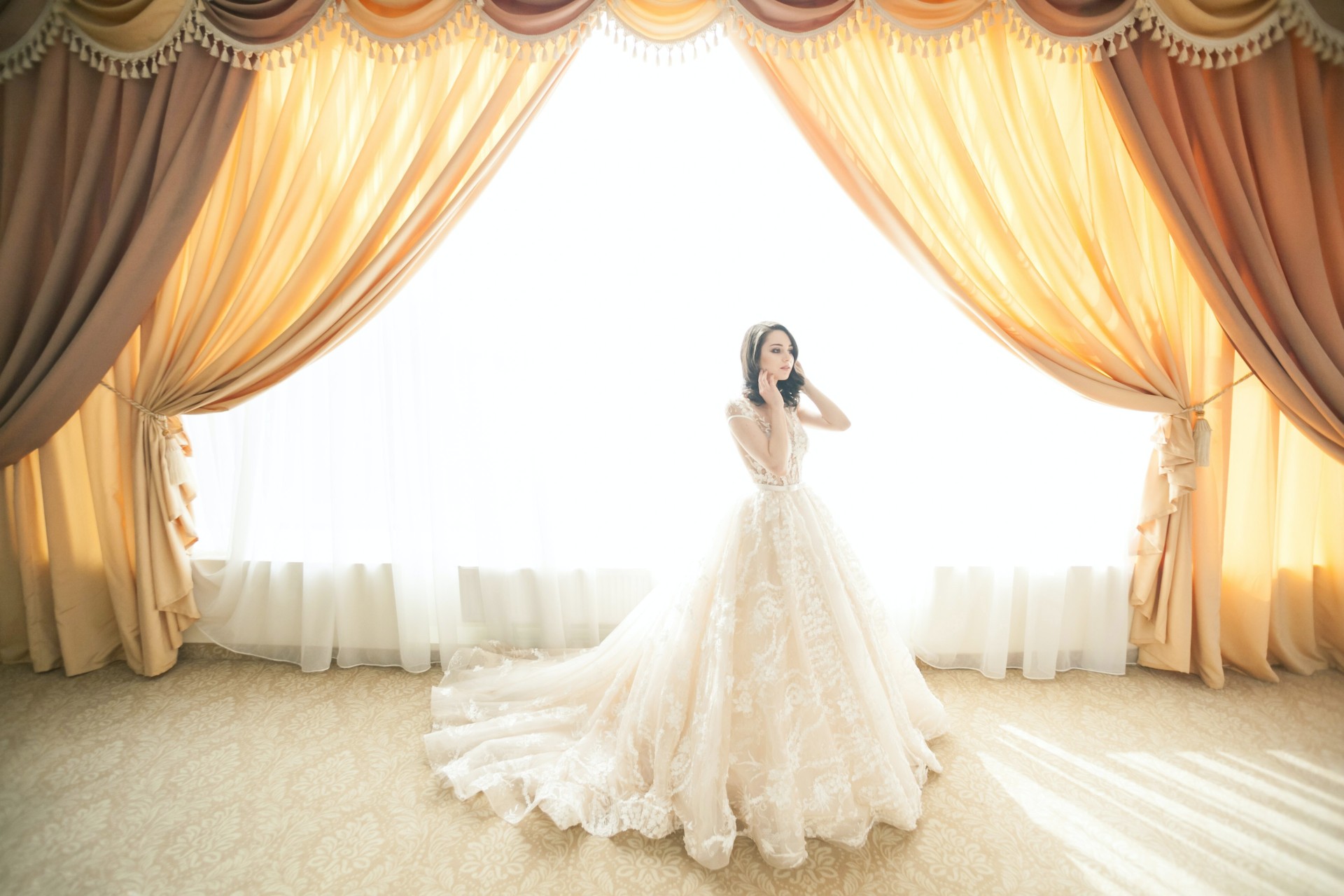 One of the beautiful gold embroidery wedding dresses against a backlit curtain with rich, warm color tones.