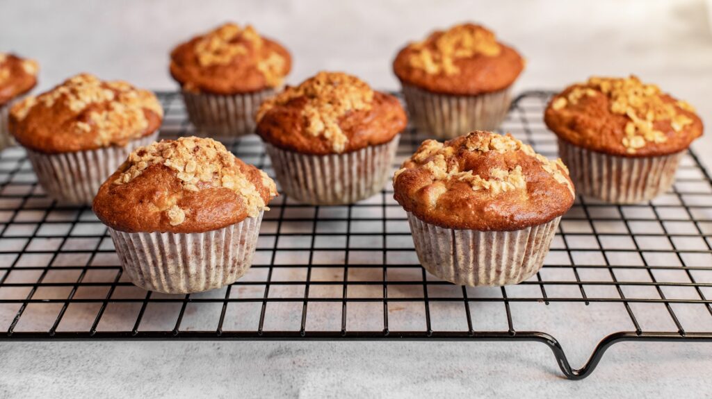 Brown muffins sit on a cooling rack.