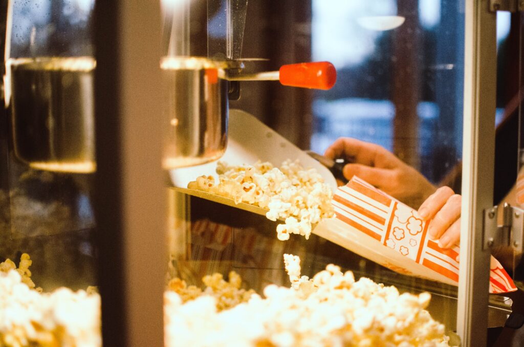 A person scoops popcorn from a machine.
