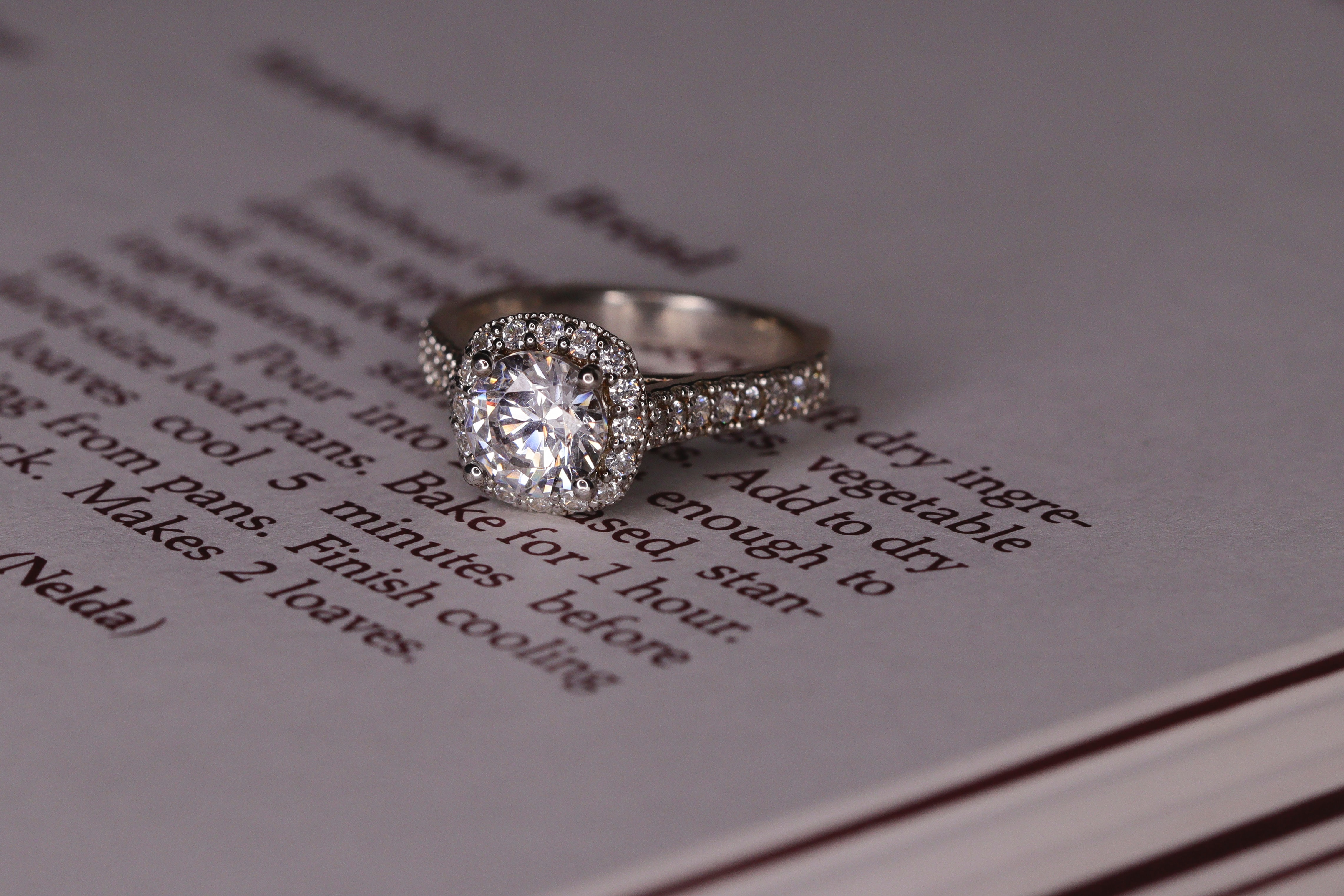 A cushion cut ring features one large stone with smaller stones surrounding the band.