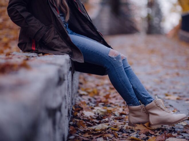 woman sitting on a rock wall in fall wearing sustainable shoes