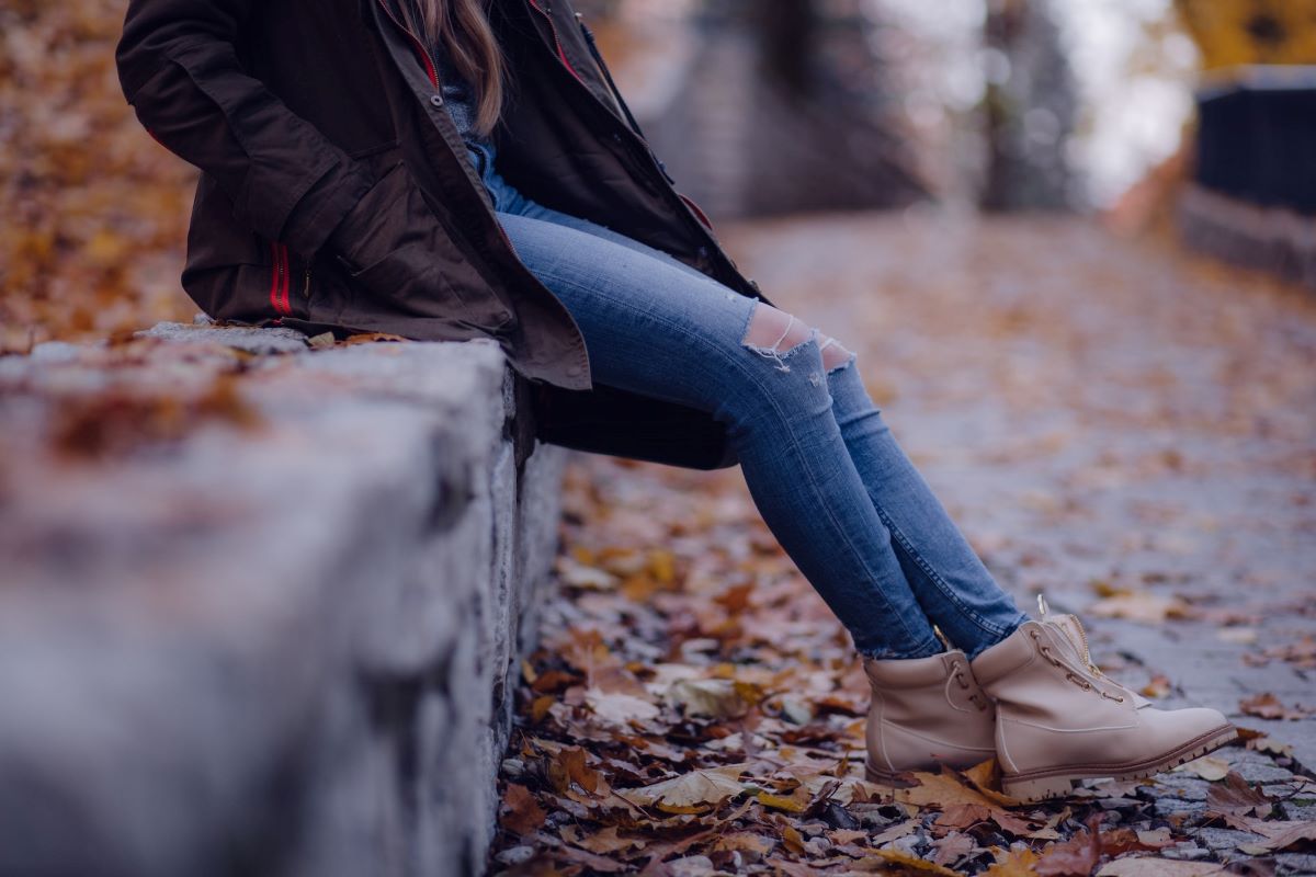 woman sitting on a rock wall in fall wearing sustainable shoes