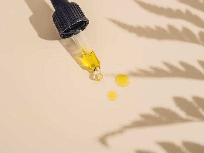a dropper on plain background holding one of the best hair oils