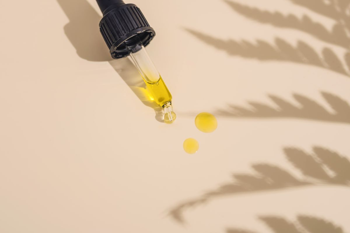 a dropper on plain background holding one of the best hair oils