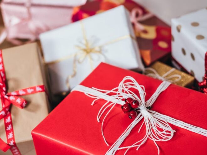 A picture of gift boxes, wrapped in reds and whites and printed paper with ribbons on them, the result of holiday shopping and wrapping.