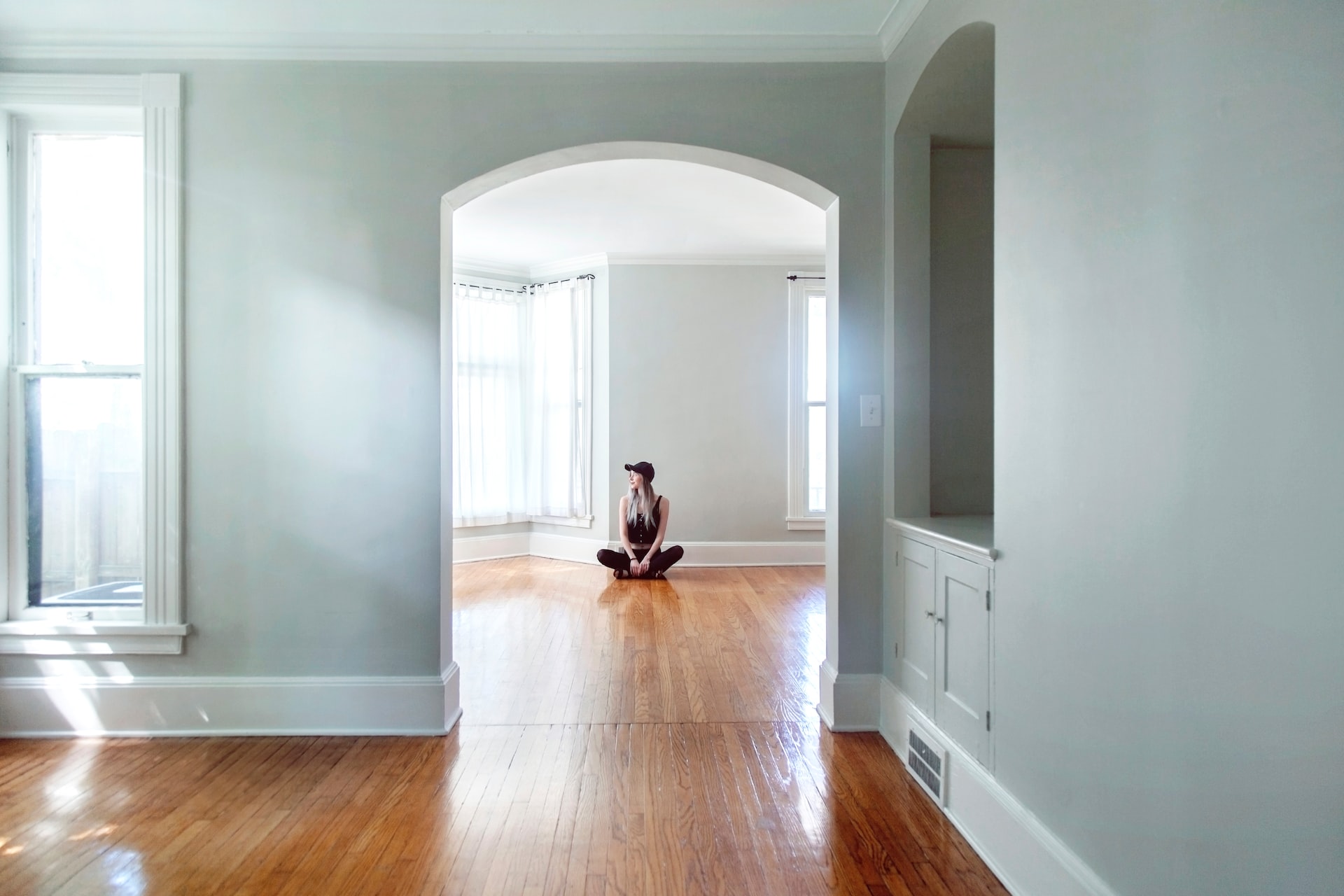 A woman sits on the floor in an empty house.