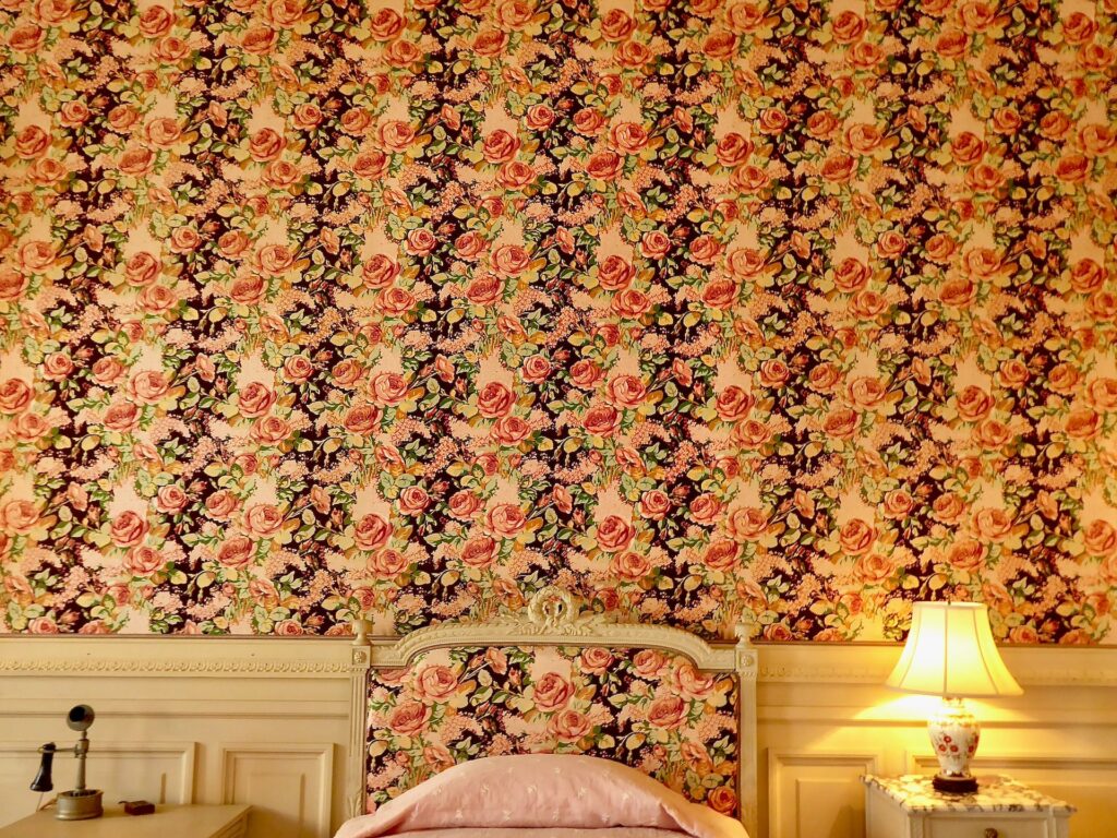 Pink and black floral wallpaper in a bedroom.