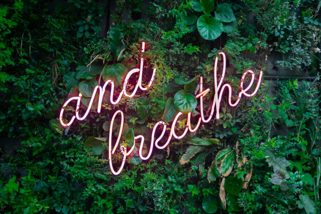 A neon sign that says "and breathe." 