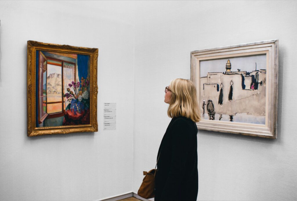 A woman looks at a painting in a museum.